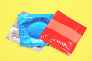 Condom isolated on yellow background - Colorful condom pack for birth control contraceptive means...