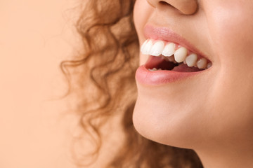 Happy woman with healthy teeth on color background, closeup