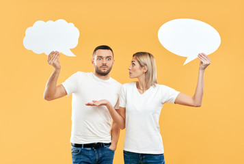Emotional woman and man holding paper thought bubbles over yellow background