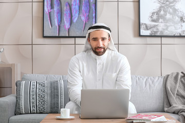 Handsome Arab man with laptop at home