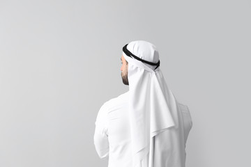 Handsome Arab man on grey background, back view