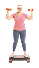 Sporty mature woman training with dumbbells on white background