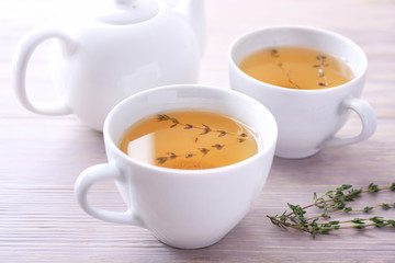 Cups of hot tea with thyme on table