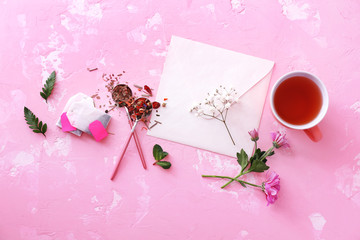 Composition with cup of hot tea and envelope on color background