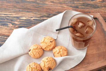 Glass of tasty iced coffee with cookies on table