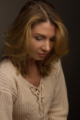 Portrait of a middle aged blonde woman in white clothes on light gray background.