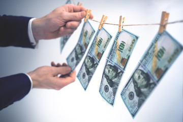 Washing money concept. Businessman is laundering money, 100 Dollar bills hanging on a washing line....