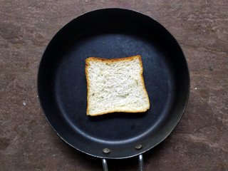 A WHITE BREAD PUT IN A  BLACK FRY PAN ON STONE BACKGROUND