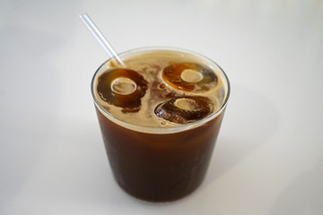 Close up glass of iced black Americano coffee on white table