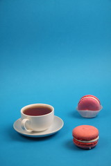 cup of tea and two macaroons on blue background. Vertical image
