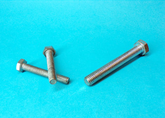 Bolts and screws for close- up construction. Chrome and shiny bolts screws on a blue background with shadow. Background construction and renovation concept.