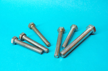 Bolts or screws made of metal close-up on a blue background. Background of stainless steel screws. Bolts for construction and repair.