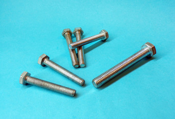 Bolts. Metal bolts close- up on a blue background. Bolts for mounting. Concept of construction and repair . The threaded bolts. Steel screws as a material for construction .