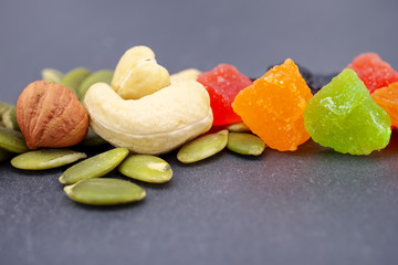 Healthy food. Dried fruits: nuts, raisins, cashews, hazelnuts, pumpkin seeds, candied fruit, on a gray background.