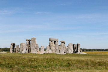 View of Stonehenge with green meadow and blue sky on a sunny day in Spring, United Kingdom