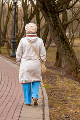Obraz premium An elderly , elegantly dressed woman walks along an alley in a public Park