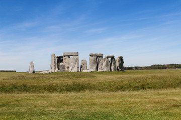 View of Stonehenge with green meadow and blue sky on a sunny day in Spring, United Kingdom