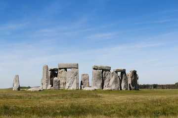 View of Stonehenge with green meadow and blue sky on a sunny day in Spring, United Kingdom