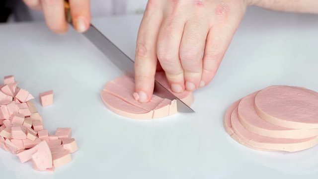 Man cuts cooked sausage mortadella