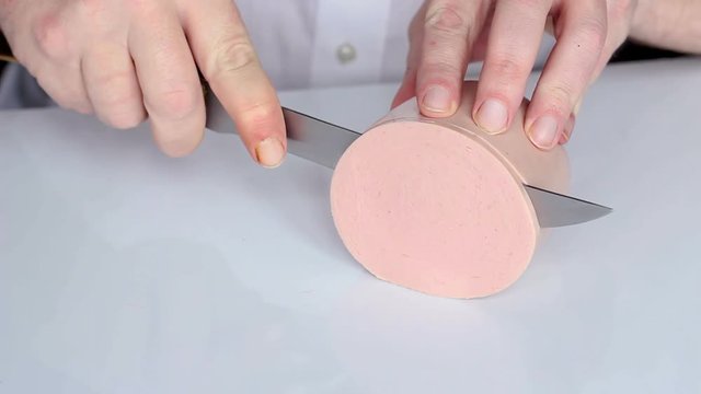 Man cuts cooked sausage mortadella