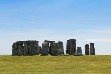 View of Stonehenge with green meadow and blue sky on a sunny day in Spring, United Kingdom