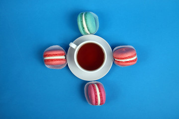 cup of tea and macaroons on blue background. Horizontal image. Tea time concept