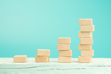 Wooden blocks stacking as step stair on white table, blue background, Ladder of success in business...