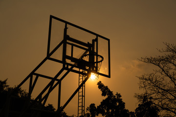 Silhouette of basketball hoop with sun in the hoop