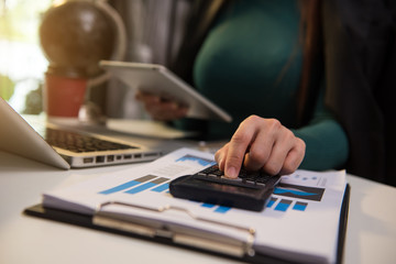 Hand business doing finances and calculate on desk about cost using on smartphone and tablet as concept