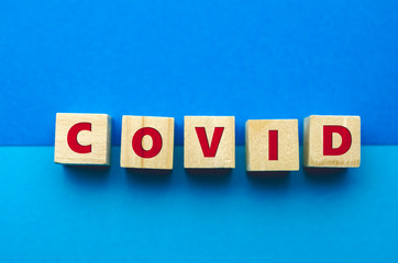 Obraz premium COVID inscription on wooden cubes on the blue background. Covid-19 pandemic concept
