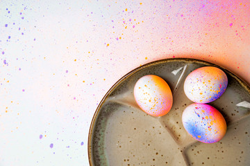 Hand colored Easter eggs painted mottled multicolor pattern on a background of multicolored pastel  - obrazy, fototapety, plakaty