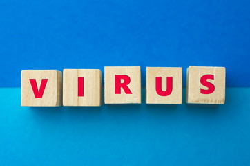 Obraz premium Virus inscription on wooden cubes on the blue background. Diseases, epidemics and pandemics concept