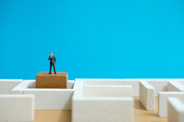 Business strategy conceptual photo - Miniature of businessman looking for solution on a labyrinth maze
