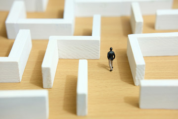 Business strategy conceptual photo - Miniature of businessman looking for solution on a labyrinth maze