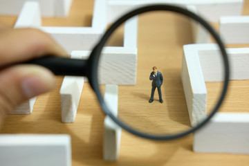Fototapeta premium Business strategy conceptual photo - Miniature of businessman looking for solution on a labyrinth maze