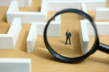 Business strategy conceptual photo - Miniature of businessman looking for solution on a labyrinth maze