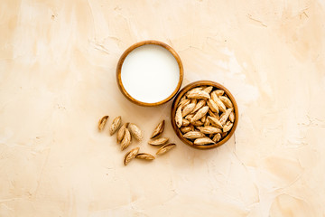 Alternative milk made from almond. Drink near unpeeled on beige table top-down