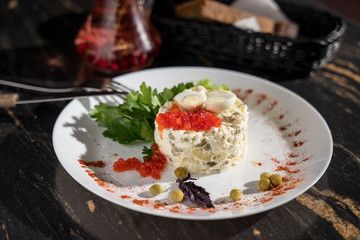 Olivier salad with red caviar from green peas of pickles, restaurant serving, bar serving