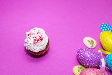 on a pink background close-up of colored Easter eggs and cupcake, holiday background