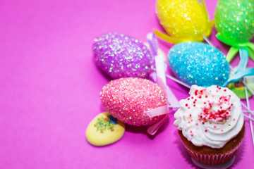 on a pink background close-up of colored Easter eggs and cupcake, holiday background