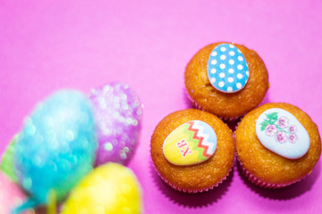 on a pink background close-up of colored Easter eggs and cupcake, holiday background