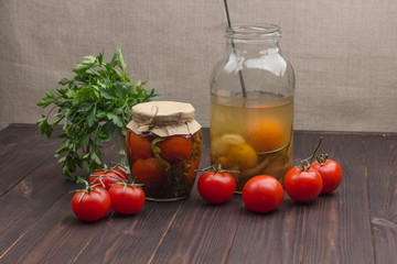 Glass jar of canned tomatoes, fresh tomatoes, green parsley, garlic and spices
