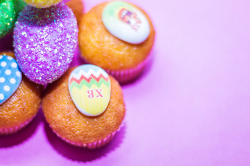 on a pink background close-up of colored Easter eggs and cupcake, holiday background