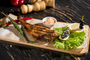 grilled fish on a plate served with slices of lemon and cream sauce