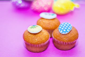 on a pink background close-up of colored Easter eggs and cupcake, holiday background