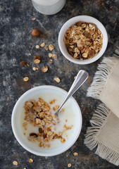 Yoghurt bowl with granola in a white bowl, wooden spoon, top view. Healthy vegan food breakfast concept.