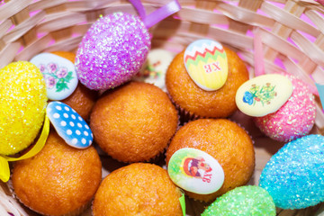 in the basket close-up colored Easter eggs and cupcakes, festive background