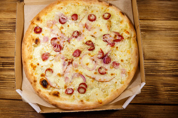 Delicious fresh pizza in cardboard box on a wooden table. Top view. Concept for home delivery of food, fast food, delivery of pizza