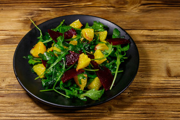Tasty salad of fresh arugula, beetroot and oranges on wooden table. Healthy food or vegetarian concept
