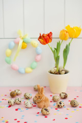 Easter wreath, bunny, quail eggs and tulips in a flower pot